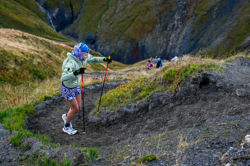 Katie Schide juoksi UTMB-polkujuoksun voittajaksi 2022. Hän nousee jyrkkää mutkittelevaa rinnettä sauvojen kanssa.